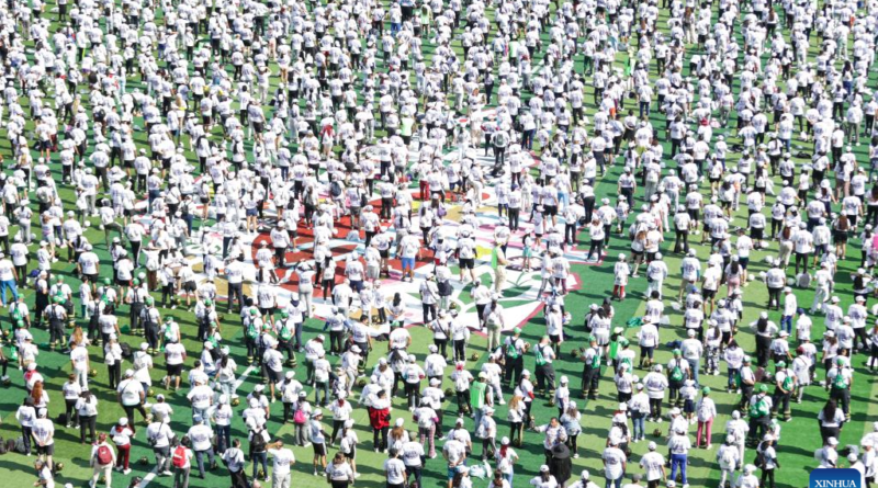 Thousands of people in green jerseys at the Zocalo;Mexico City ; Mayor Clara Brugada holding the Guinness World Record certificate; Participants practicing soccer drills.