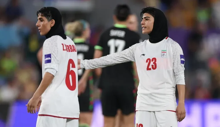 Mona Hamoudi and Zahra Sarbali on the pitch; Iranian women; MediaXTrand; Iranian fans in Australia holding flags; The Iranian national women's team standing in silence